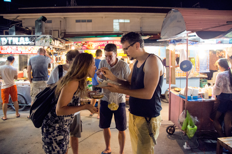Guy feeding girl on food market