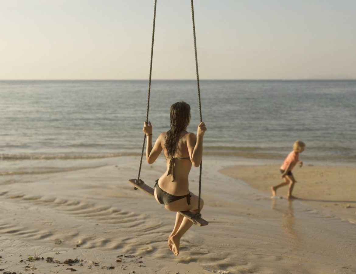 Girl_on_swing_on_beach_with_child_running