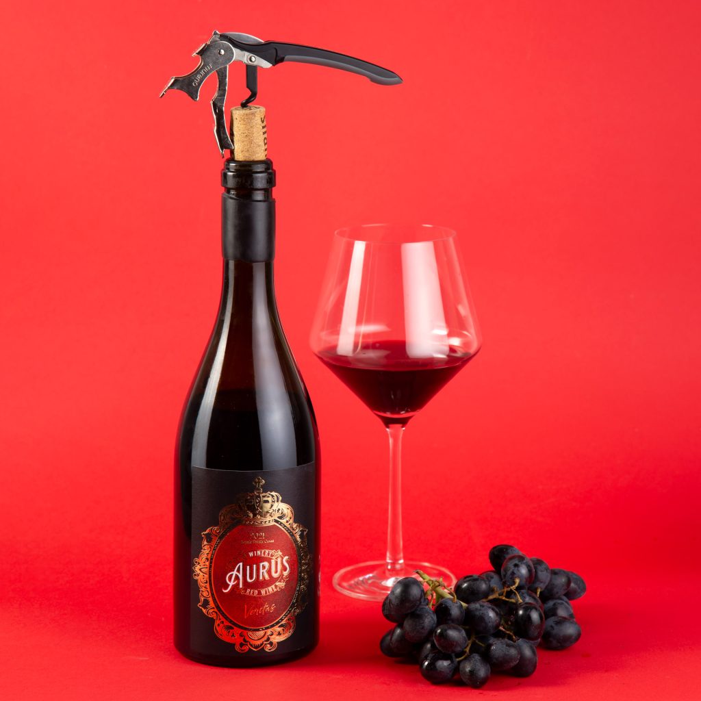 A bottle of red wine with Wine glass and grapes on red background